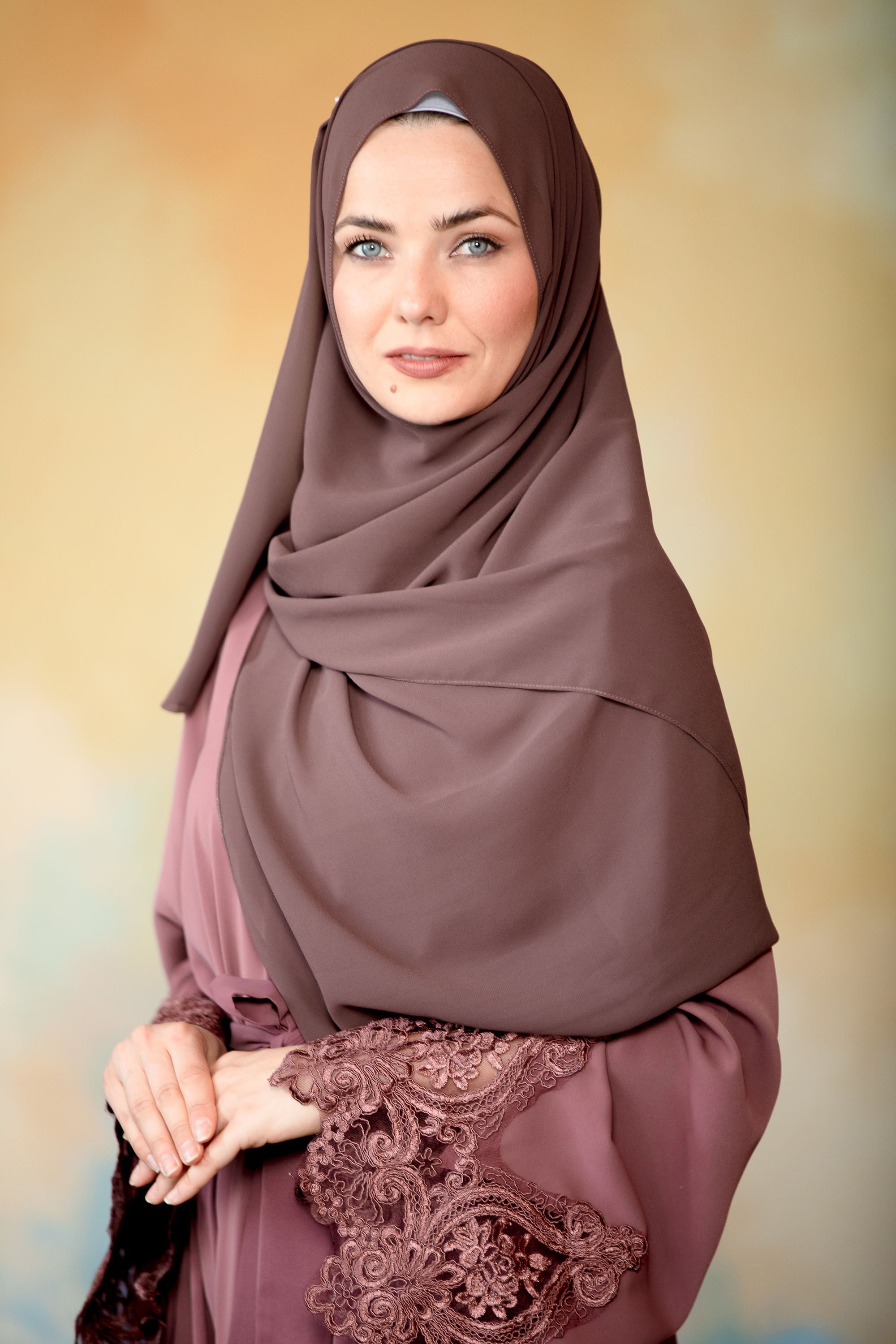 Woman in mauve hijab and lace-cuff dress with dark brown chiffon