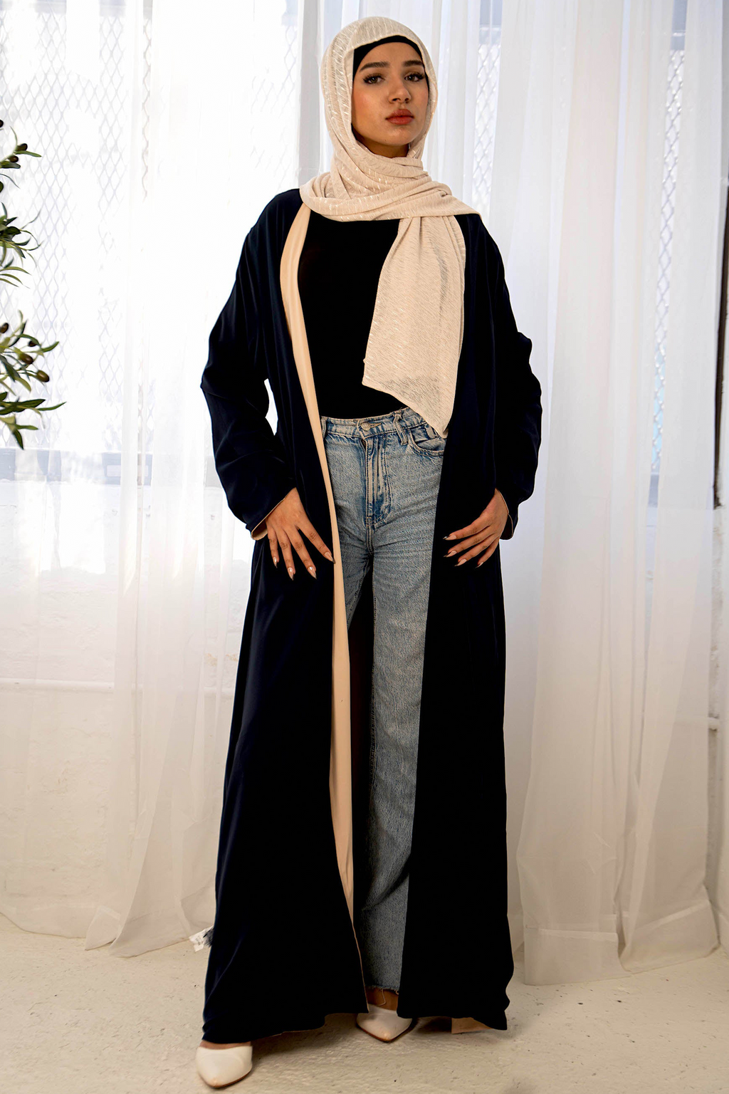 Woman in navy reversible open abaya with cream hijab and jeans